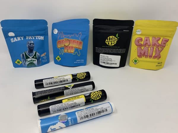 Premium cannabis products including flower, pre-rolls, edibles, and vape cartridges displayed on table at Happy Time Dispensary